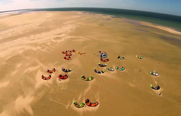 Une vingtaine de kites sur le sable vu du ciel.