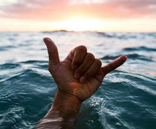Une main dans l'eau qui fait le signe de « hang loose ».